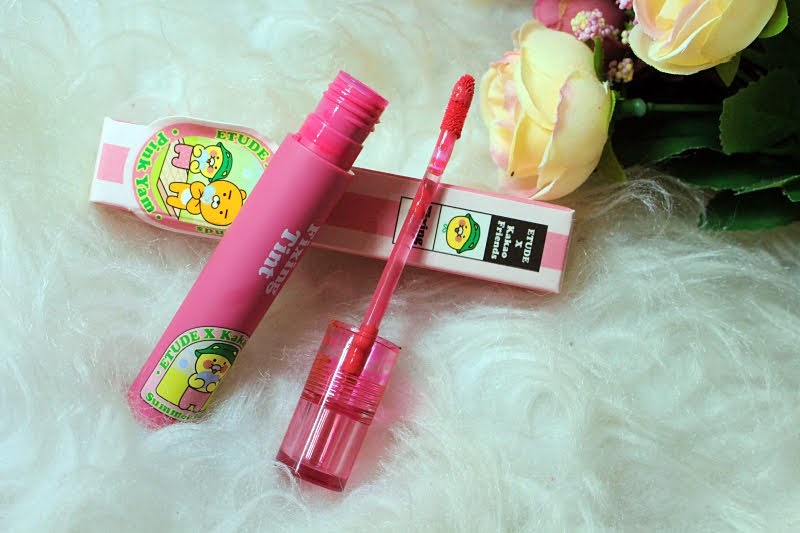 Tubo rosa de gloss labial ao lado de uma flor, destacando a beleza e a delicadeza dos produtos de maquiagem.